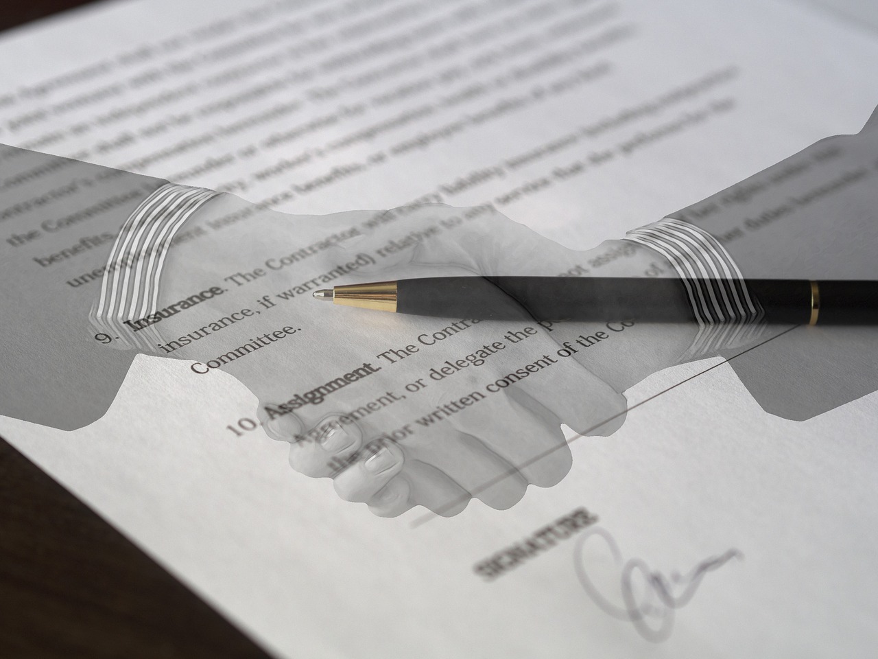 Legal agreement with two transparent hands shaking over it